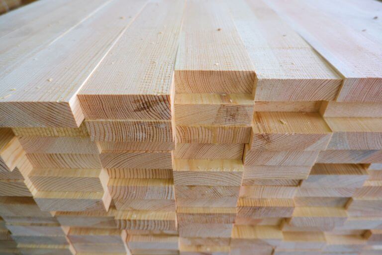 Top-end view of a stack of three-layer wooden glued laminated timber, showcasing the quality and durability of Solid Wood Panels.